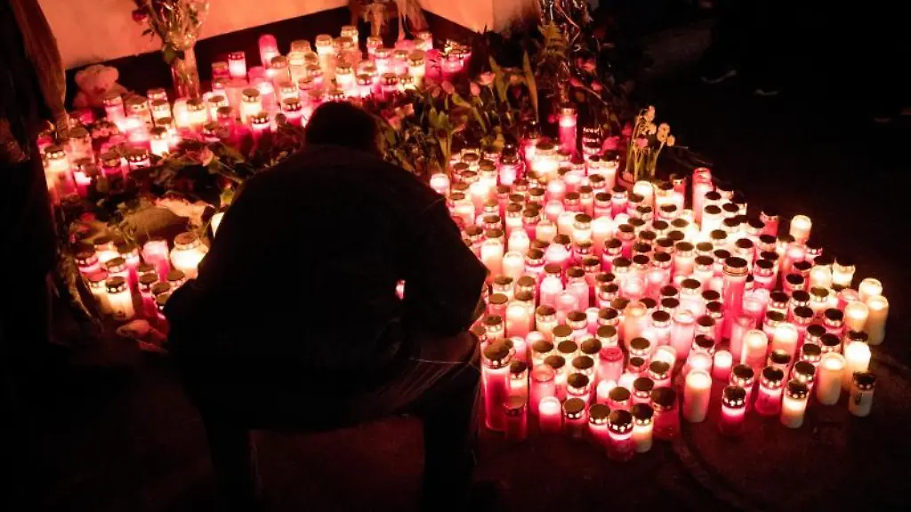 Ein-Mann-kniet-vor-dem-Haus-einer-getoeteten-21-jaehrigen-an-einem-Meer-aus-Kerzen-die-von-den-Teilnehmern-eines-Trauermarsches-zuvor-dort-abgestellt-worden-waren