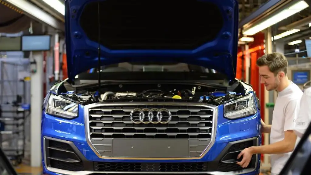 Ein-Mitarbeiter-bringt-an-einem-Fliessband-im-Audi-Werk-das-Frontende-an-einem-Audi-an