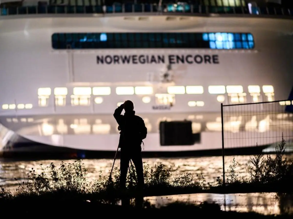 Ein-Mann-steht-vor-dem-Becken-der-Meyer-Werft-und-fotografiert-das-Kreuzfahrtschiff-Norwegian-Encore