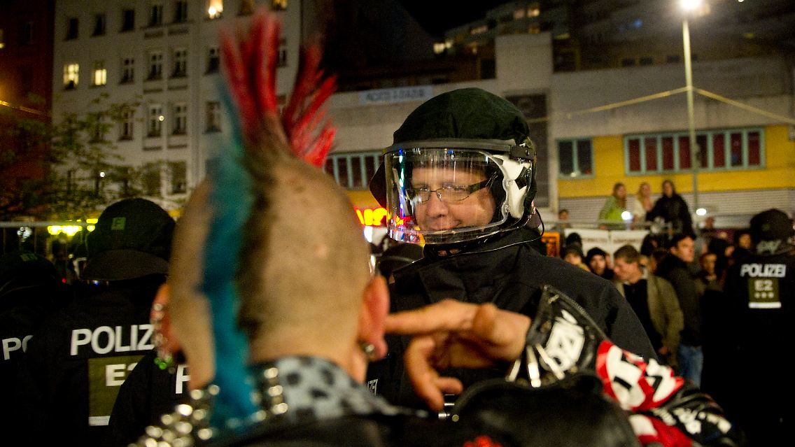 Enstpannte Kommunikation statt heftiger Auseinandersetzung: Ein Punk und ein Beamter beim Plausch am Kottbusser Tor in Berlin-Kreuzberg.