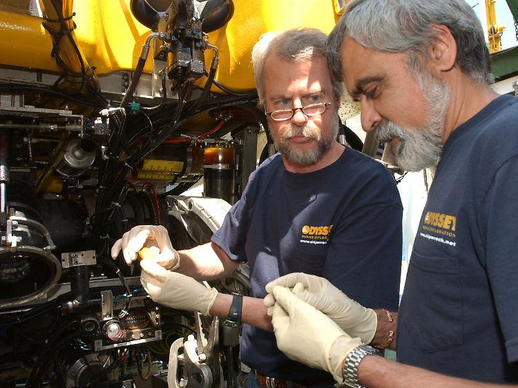 Die Odyssey-Gründer Greg Stemm (l) und Projektleiter Tom Dettweiler untersuchen eine Münze vom "Black Swan"-Fundort.