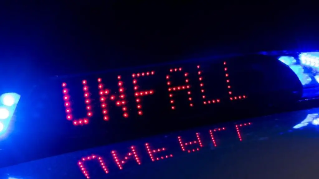 Zwischen-den-Blaulichtern-auf-einem-Polizeifahrzeug-warnt-eine-Leuchtschrift-vor-einem-Unfall