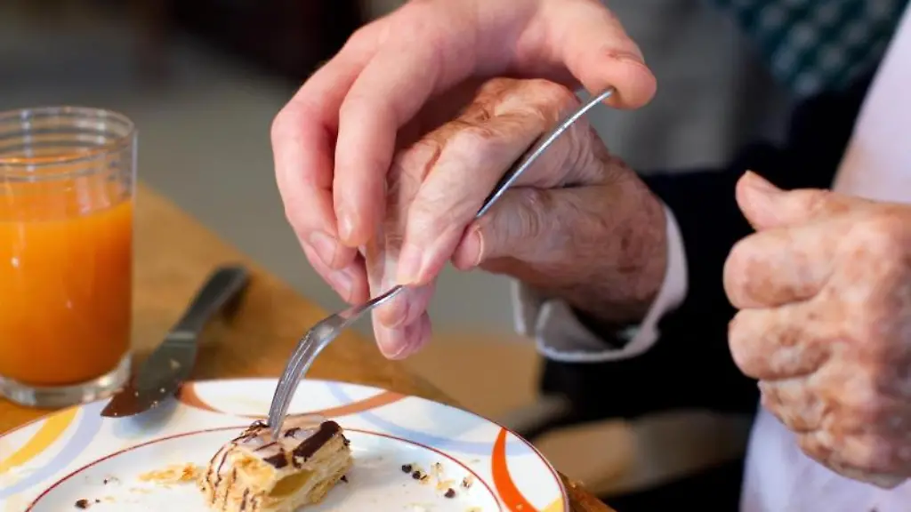 Ein-junger-Mann-der-ein-Freiwilliges-Soziales-Jahr-FSJ-absolviert-hilft-einer-Bewohnerin-einer-Wohngemeinschaft-fuer-Demenzkranke