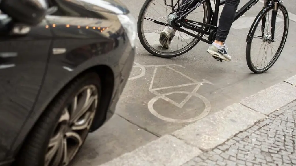 Eine-Radfahrerin-umfaehrt-ein-auf-dem-Radweg-stehendes-Auto