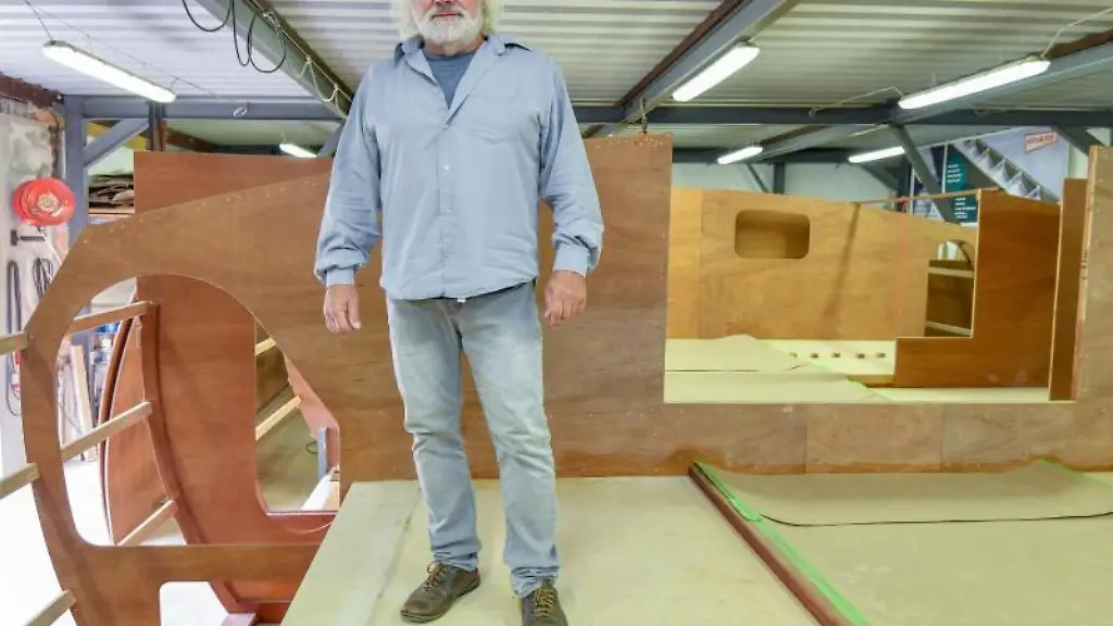 Frank-Ladewig-Praesident-der-Organisation-FYD-Adventure-steht-in-einer-Halle-auf-dem-Rohbau-eines-Katamarans