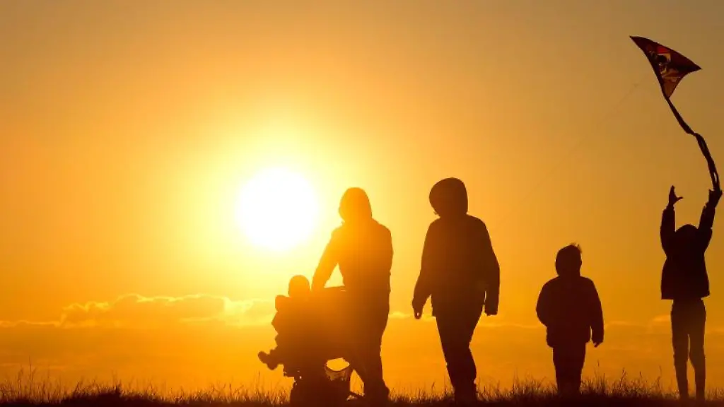 Eine-Familie-mit-Kinderwagen-und-einem-Drachen-geht-bei-Sonnenuntergang-ueber-einen-Weg