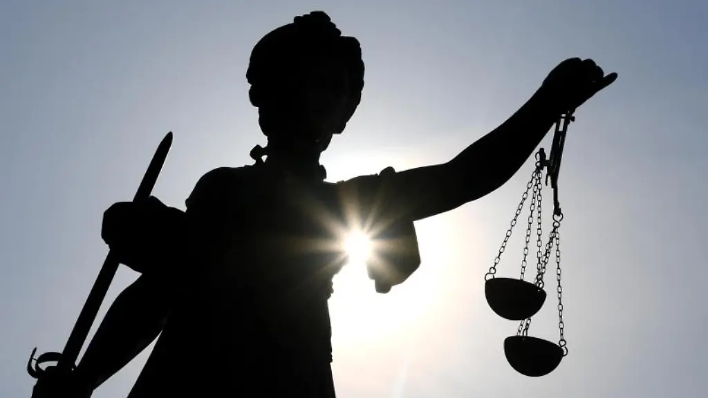 Die-Statue-der-Justitia-wird-von-hinten-von-Sonnenstrahlen-angeleuchtet