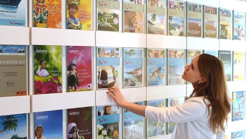 Eine-Frau-blickt-in-einem-Reisebuero-auf-Kataloge