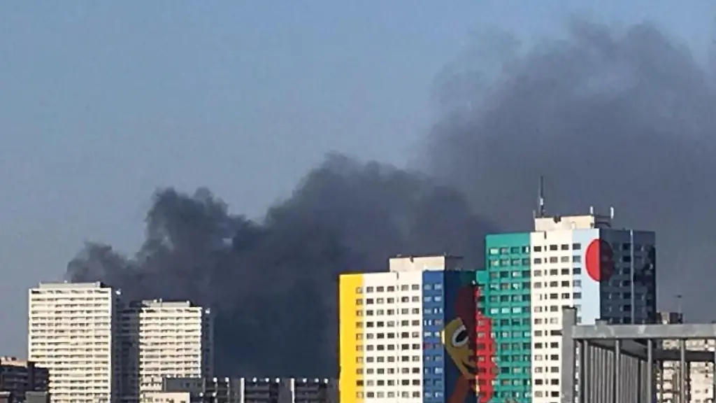 Dunkler-Rauch-steigt-hinter-den-Hochhaeusern-nahe-der-Storkower-Strasse-auf