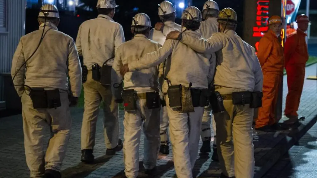 Bergleute-umarmen-sich-auf-dem-Gelaende-einer-Zeche