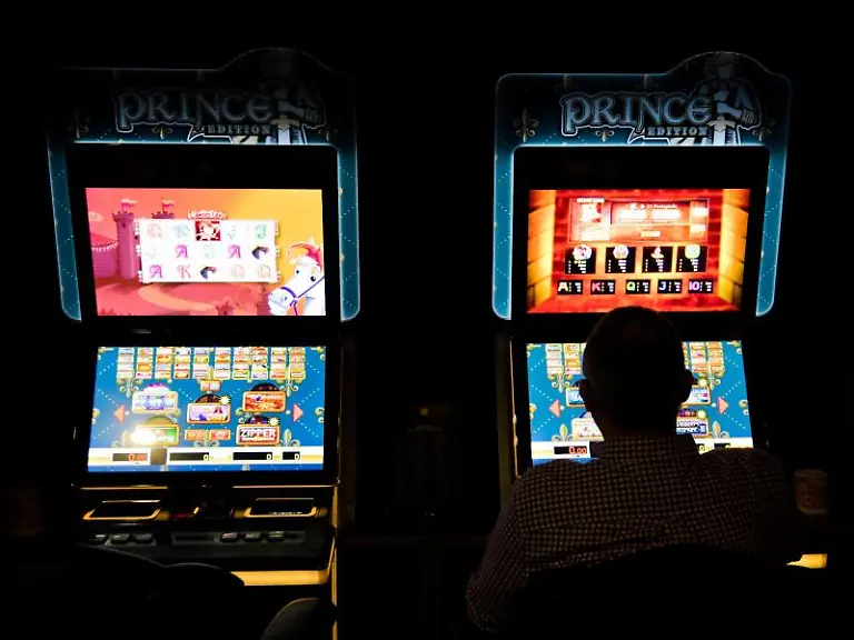 Ein-Mann-sitzt-an-Spielautomaten-in-einer-Spielhalle