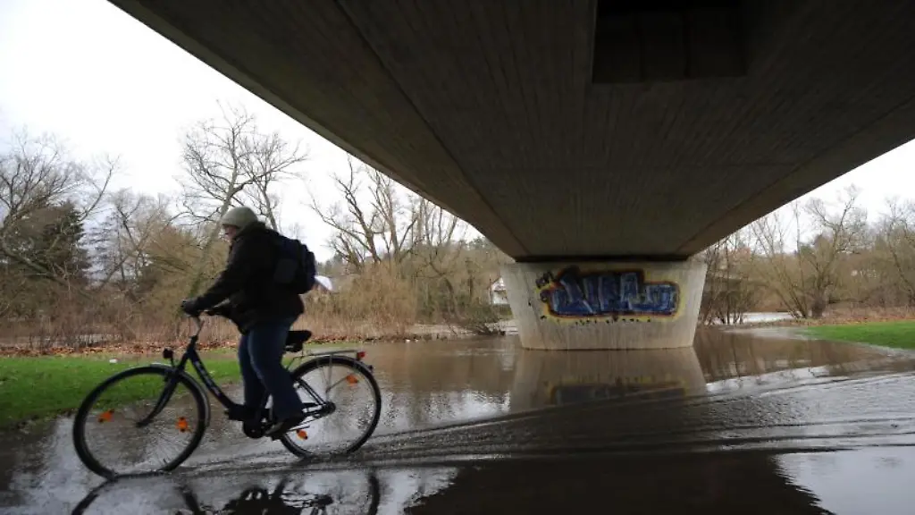 Eine-Frau-faehrt-mit-ihrem-Rad-in-Melsungen-ueber-einen-von-der-Fulda-ueberfluteten-Radweg
