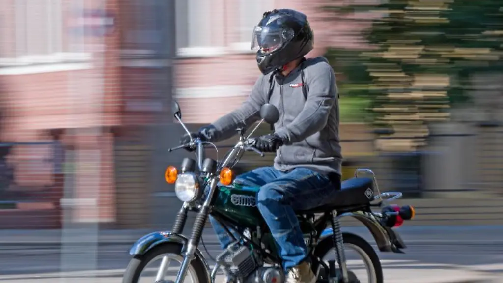 Ein-Fahrlehrer-faehrt-auf-einem-Simson-S51-Moped-durch-die-Stadt