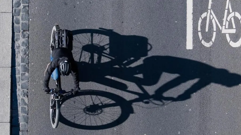 Eine-Fahrradfahrerin-faehrt-ueber-eine-Strasse-am-Rathaus-mit-einer-Markierung-fuer-Fahrraeder