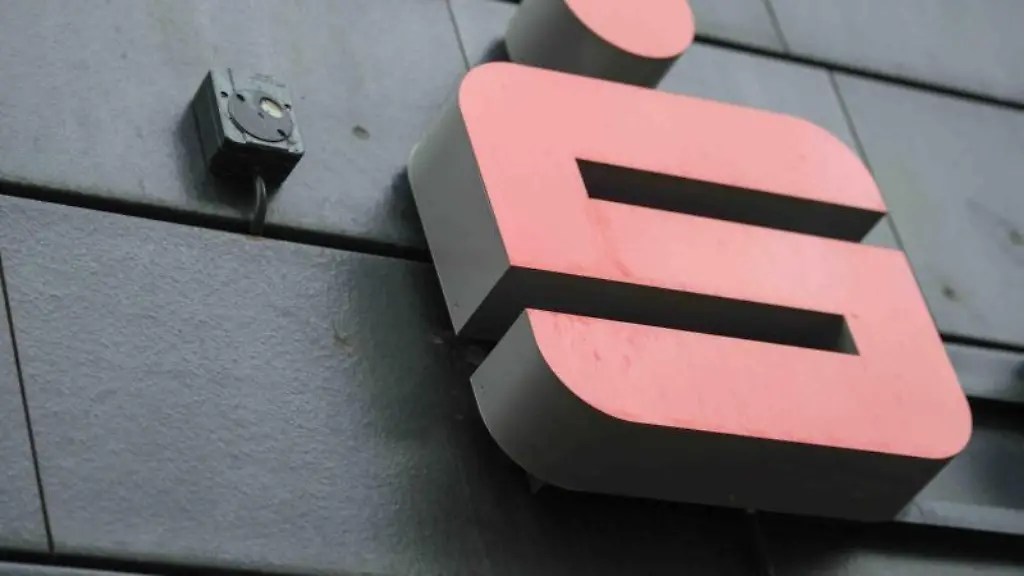 Ein-Logo-der-Sparkasse-haengt-an-einer-Filiale
