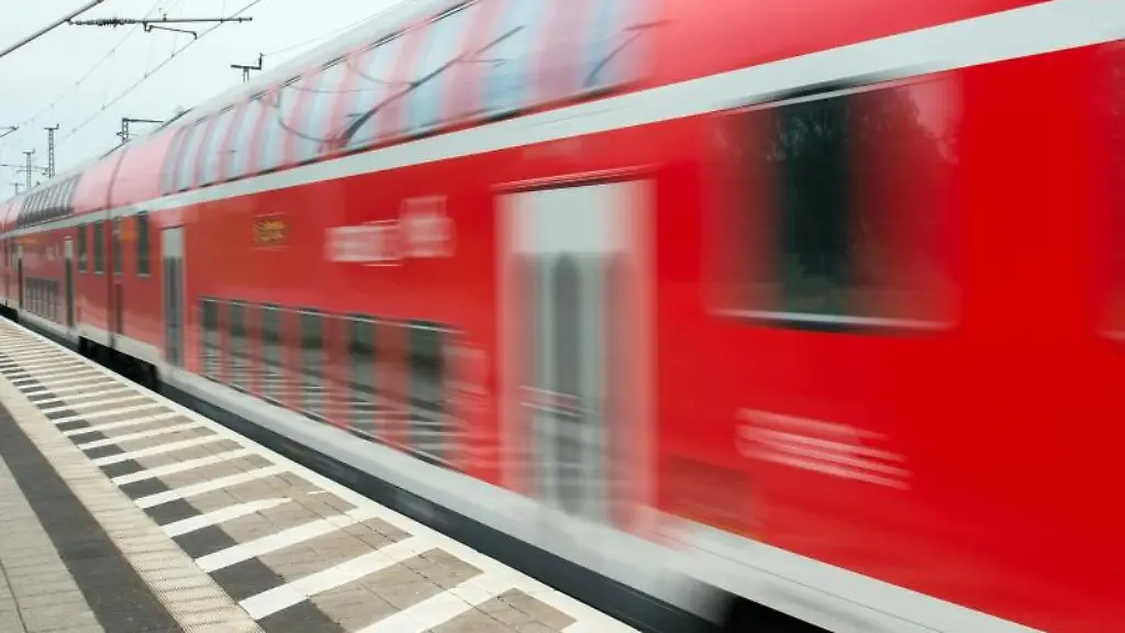 Ein-Regionalexpress-der-Deutschen-Bahn-faehrt-an-einem-Bahnhof-vorbei