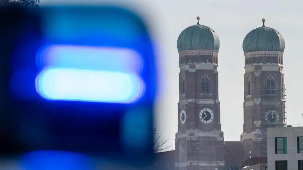 Ein-Blaulicht-einer-Polizeistreife-ist-vor-den-Tuermen-der-Frauenkirche-in-Muenchen-zu-sehen