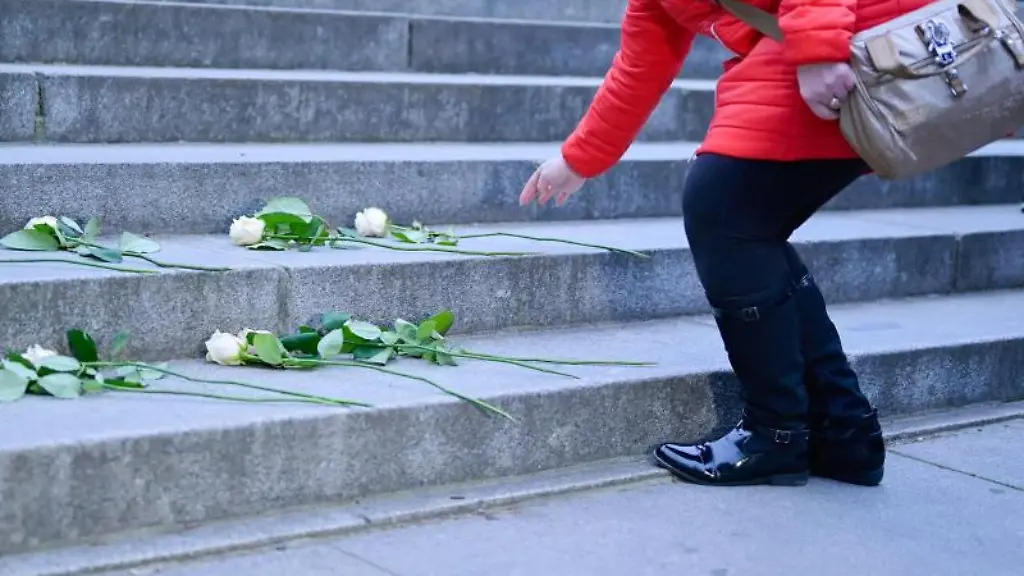 Eine-Frau-legt-bei-Kundgebungen-am-Luther-Denkmal-in-Worms-eine-Blume-auf-die-Treppe