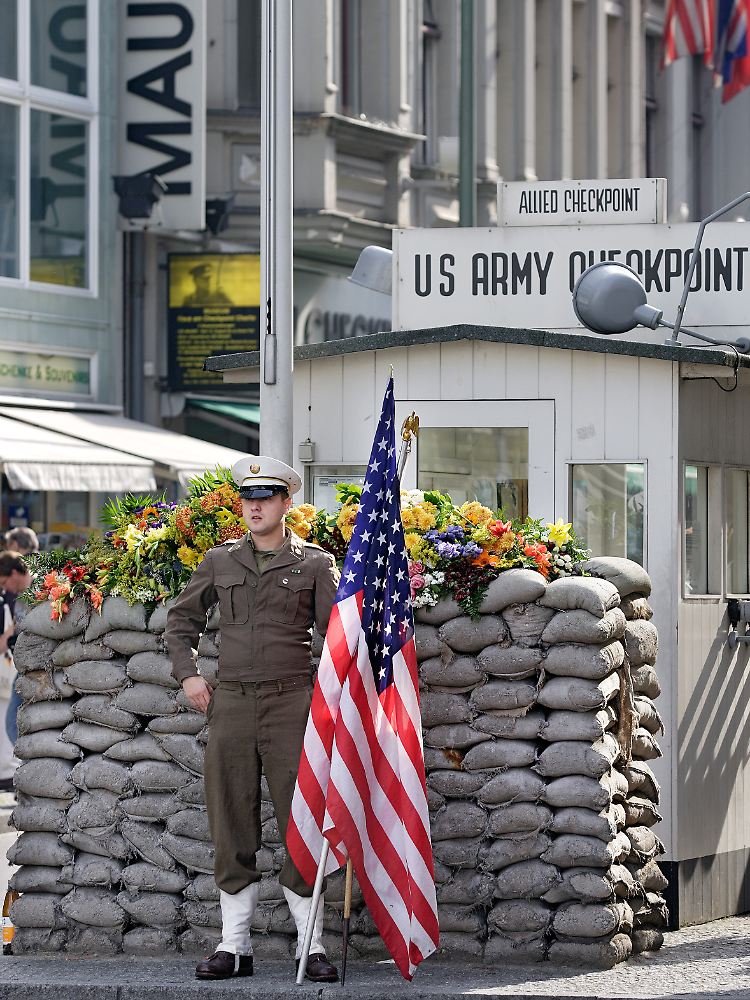 Alltägliche Inszenierung: Am Checkpoint Charlie posieren lebende Fotomotive mit US-amerikanischer Flagge.
