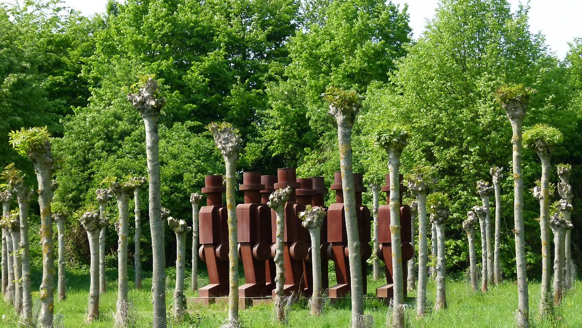In Reih' und Glied: Stählerne Figuren marschieren zwischen Bäumen durch den Park des Museums.