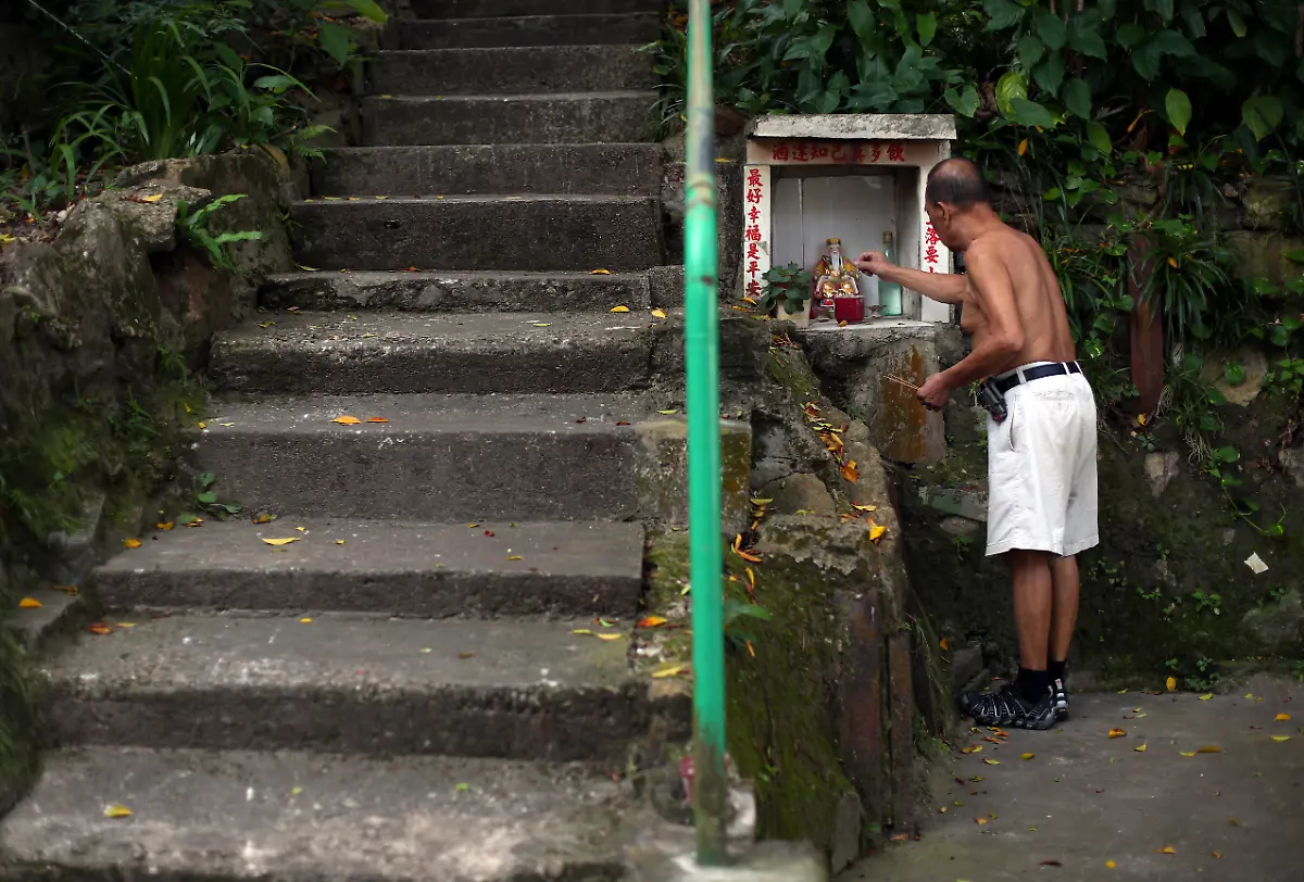 Tim-Wan-Kwok-72-entzuendet-eine-Kerze-vor-der-Statue-des-chinesischen-Gottes