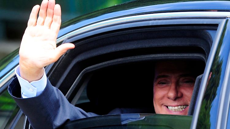 Berlusconi winkt nach der Abstimmung aus seinem Auto heraus..