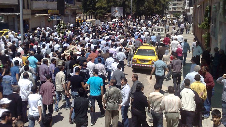 Trauergäste in Homs tragen die Särge der getöteten Demonstranten durch die Straßen.