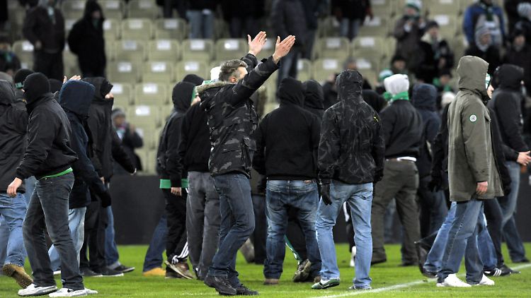 Vermummte Fans stürmen das Spielfeld.