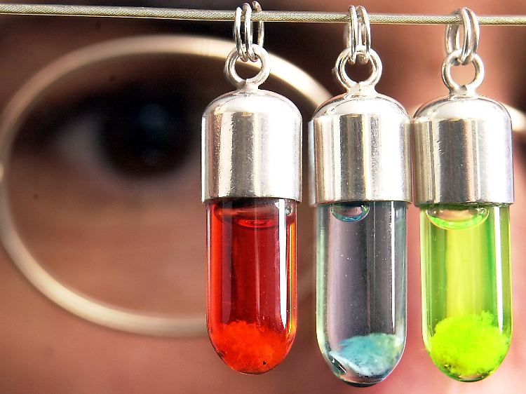 Ein Molekularbiologe begutachtet DNA-Fäden in kleinen Glasanhängern.