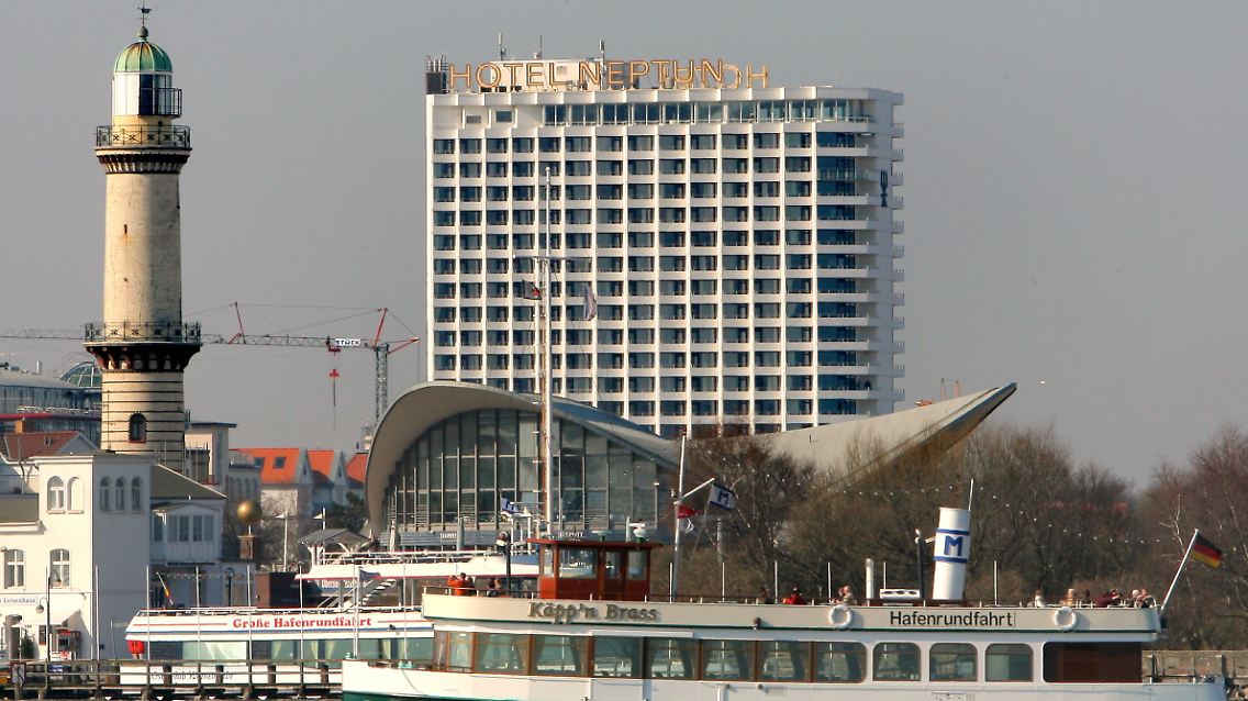 Hotel Neptun im Ostseebad Warnemünde mit Leuchtturm, Teepott und Ausflugsschiff.