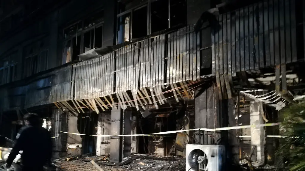 In-this-photo-released-by-Xinhua-News-Agency-a-man-walks-past-the-Zuxintang-Foot-Massage-Parlor-damaged-by-a-fire-in-Tiantai-County-east-China-s-Zhejiang-Province-Monday-Feb-6-2017-The-fire-at-the-massage-parlor-on-Sunday-killed-and-injured-dozens-of-people-state-media-reported
