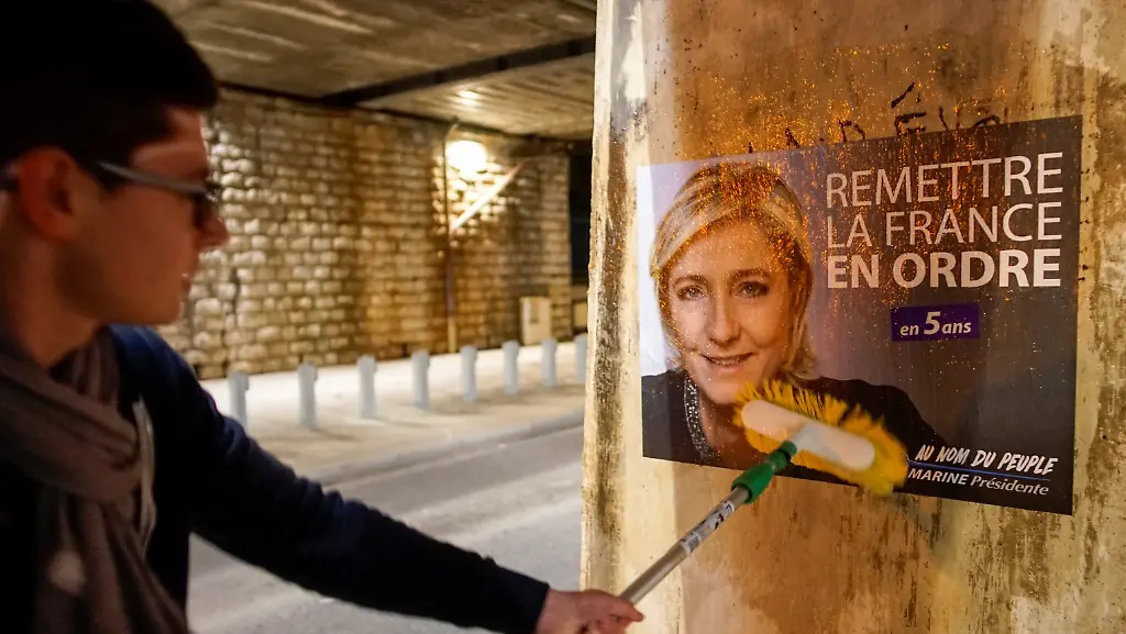 A-member-of-the-National-Front-youths-puts-up-a-poster-of-Marine-Le-Pen-French-National-Front-FN-political-party-leader-and-candidate-for-the-French-2017-presidential-election-ahead-of-a-2-day-FN-political-rally-to-launch-the-presidential-campaign-in-Lyon-France-February-2-2017
