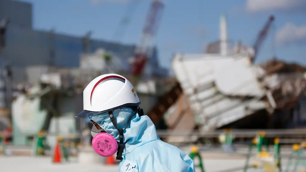 A-Tokyo-Electric-Power-Co-TEPCO-employee-wearing-a-protective-suit-and-a-mask-walks-in-front-of-the-No-1-reactor-building-at-the-tsunami-crippled-Fukushima-Dai-ichi-nuclear-power-plant-in-Okuma-Fukushima-Prefecture-northeastern-Japan-Wednesday-Feb-10-2016-In-one-month-Japan-is-marking-the-fifth-anniversary-of-a-devastating-earthquake-and-tsunami-that-hit-on-March-11-2011-and-left-nearly-19-000-people-dead-or-missing-turned-coastal-communities-into-wasteland-and-triggered-a-nuclear-crisis