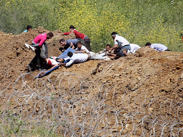 Demonstranten ziehen einen Verwundeten aus dem syrisch-israelischen Grenzgebiet.