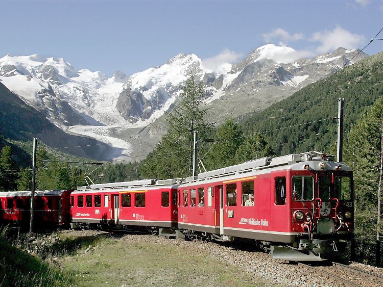 Ein Zug der Rhätischen Bahn (RhB) fährt auf der Bernina-Strecke durch den Schweizer Kanton Graubünden - im Hintergrund der Morteratsch-Gletscher: Wenn die Übernachtungspreise weiter steigen, dürften sich viele Touristen schnell zur Weiterreise entscheiden.