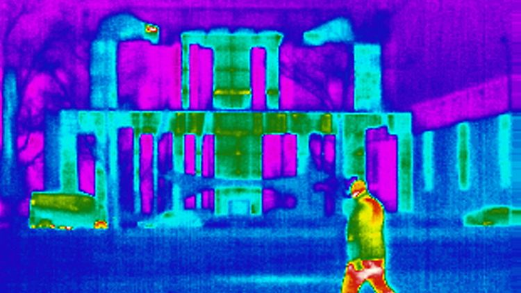 Wärmebild eines Passanten vor dem Bundeskanzleramt. Weiß, Gelb und Rot sind wärmer als Lila, Blau und Türkis.