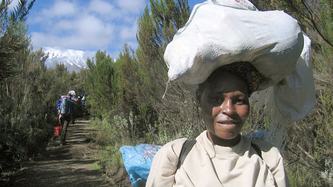 Bis zu 20 kg Gepäck auf Kopf und Rücken schleppt die Trägerin Esther Crispin auf den Kilimandscharo hinauf. Die 30 Jahre alte Tansanierin gehört zu den wenigen Frauen, die am höchsten Berg Afrikas als Trägerinnen arbeiten.