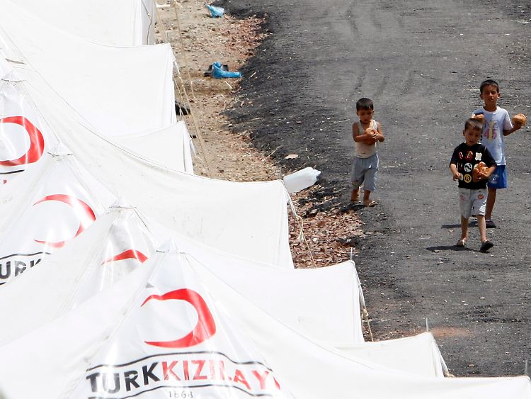 Kinder tragen in einem Flüchtlingscamp in der Türkei Brot. In den Lagern an der Grenze zu Syrien harren Tausende Menschen aus.