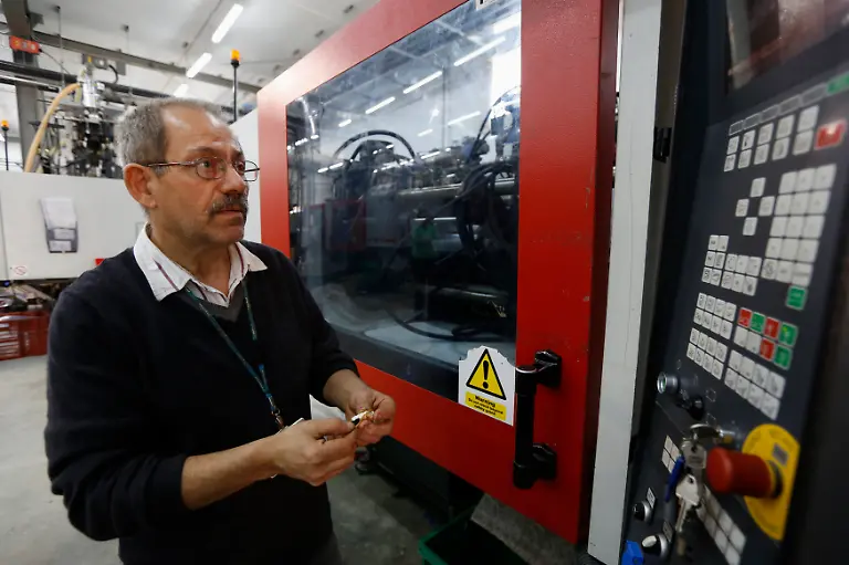 Charles-Borg-62-visually-examines-a-Playmobil-figure-next-to-an-injection-moulding-machine