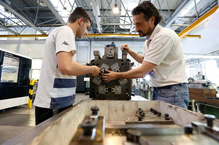 A-supervisor-R-shows-a-worker-how-to-service-part-of-an-injection-moulding-machine