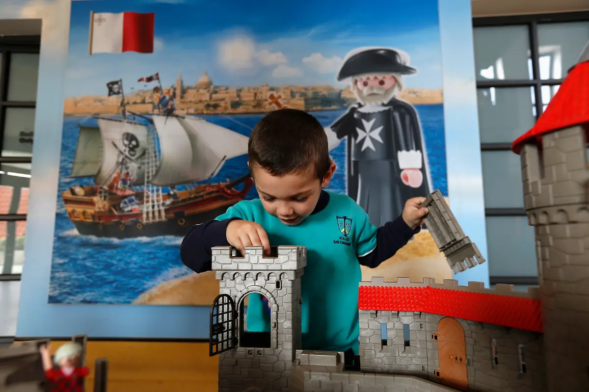 A-child-plays-in-front-of-a-poster-showing-a-Playmobil-Knights-of-Malta-Grand-Master-figure