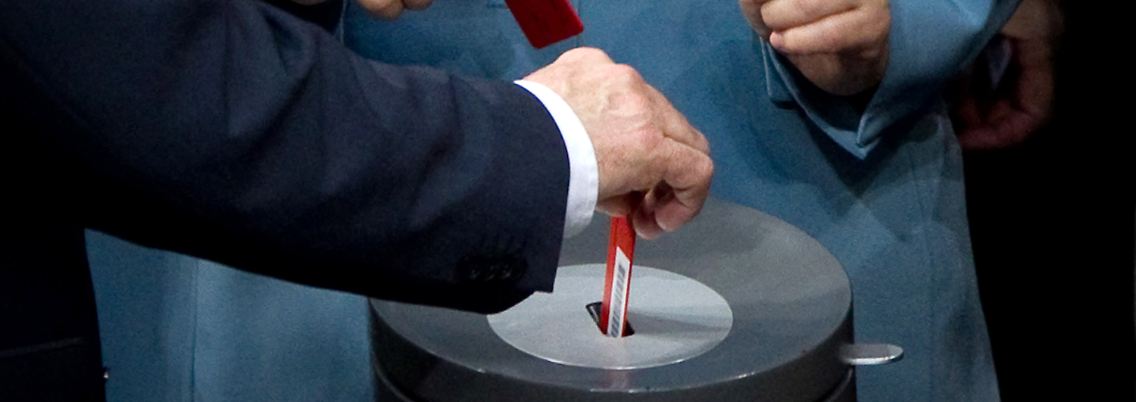 Die Kanzlerin wirft ihre Stimmkarte ein.