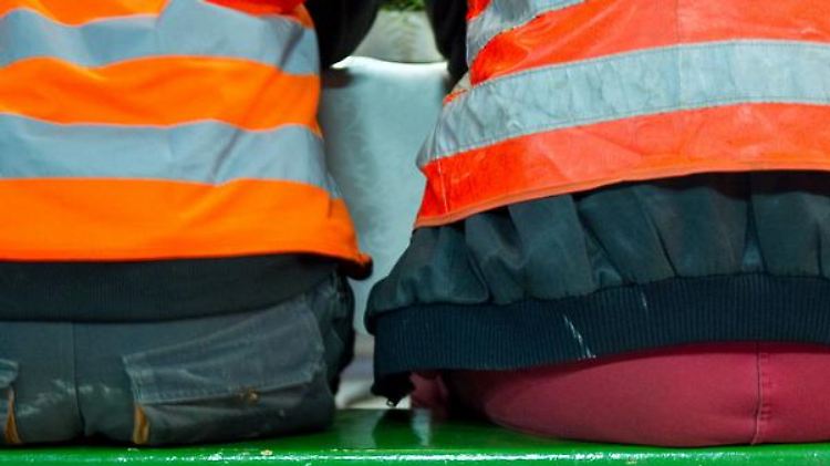 Helm und Warnweste sind aus Sicherheitsgründen angebracht, was Bauarbeiter drunter tragen, ist dagegen egal.