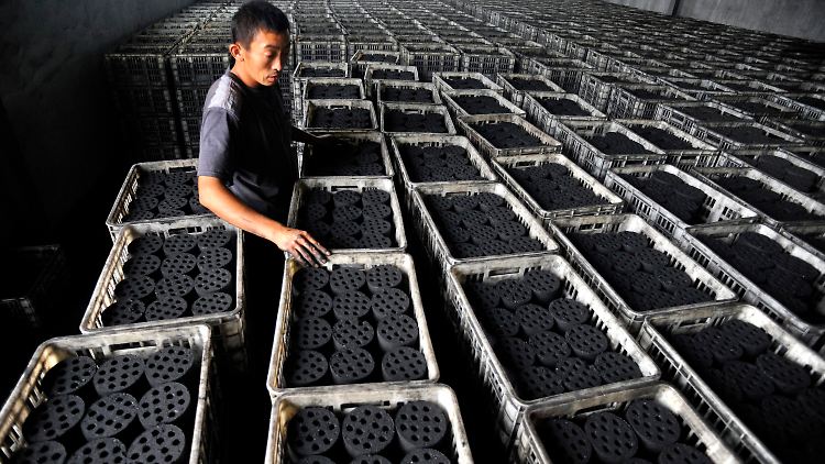 Ein Arbeiter stapelt in einer Fabrik in China Kohlebriketts. Mit dem Anstieg der Kohleverbrennung in China gelangen riesige Mengen Schwefeloxide in die Luft.