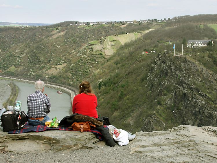 Von einem Felsen aus genießt dieses Paar bei Oberwesel in Rheinland-Pfalz einen Panoramablick auf die Loreley und das Rheintal.