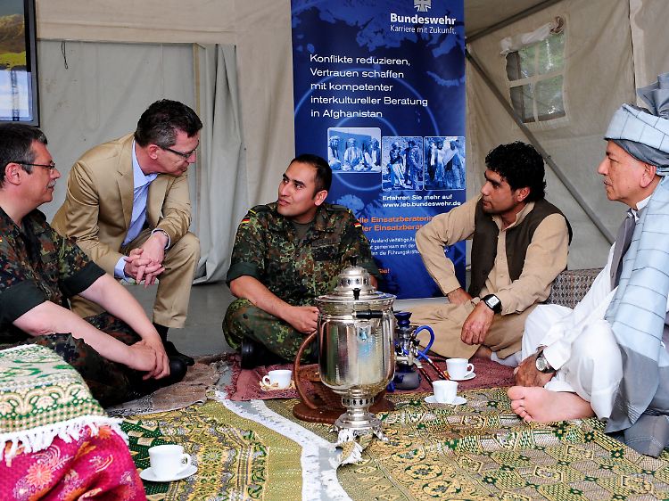 De Maiziere (CDU, 2.v.r.) nimmt in einer Bundeswehrbasis in Rheinland-Pfalz an einer nachgestellten Szene der "interkulturellen Einsatzberatung der Bundeswehr in Afghanistan" teil.