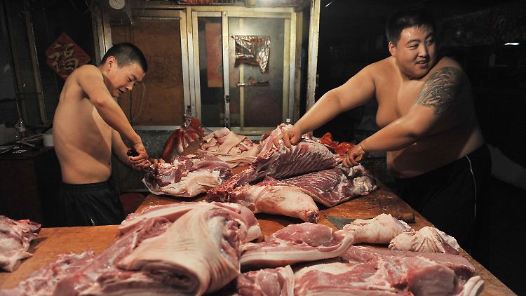 Ohne Arbeitshemd und Schutzhandschuhe: Fleischer zerlegen ein Schwein in einem Markt im chinesischen Shenyang.