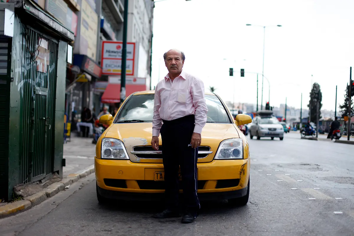 Dasalakis-Theodoros-60-a-taxi-driver-poses-for-a-picture-in-front-of-his-taxi-at-the-port-in-Athens-March-28-2012-When-asked-how-he-had-been-affected-by-the-economic-crisis-Theodoros-replied-I-share-the-taxi-with-my-son-so-we-can-work-24-hours-a-day-between-us-to-make-things-work-Picture-taken-March-28-2012