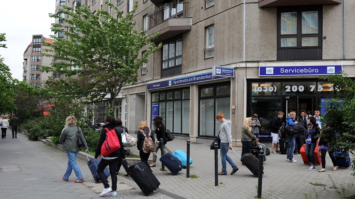 Eine Reisegruppe vor einem Servicebüro für die Vermietung von Appartments in der Behrenstraße in Berlin - Mitte.