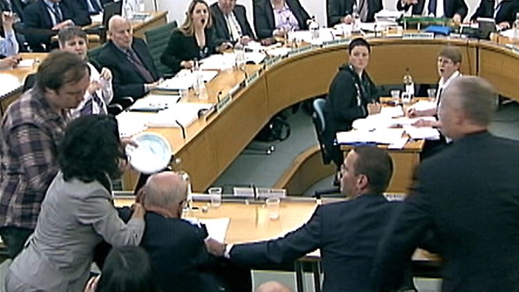 Jonathan May-Bowles nähert sich mit einer Schüssel voll Rasierschaums Rupert Murdoch.